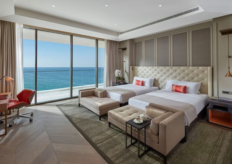 Twin-bed bedroom of the Two Bedroom Sea View Suite with floor-to-ceiling windows over the Arabian Gulf