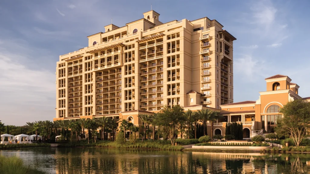The Mediterranean-style tower of Four Seasons Resort Orlando reflected in the lakefront at golden hour