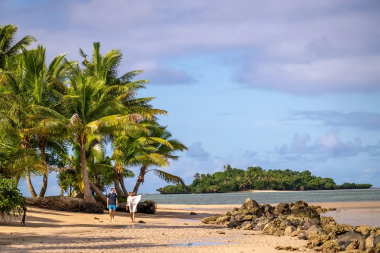 A quiet stretch of beach at sunset near Jean-Michel Cousteau Resort Fiji, with palm trees framing the shoreline