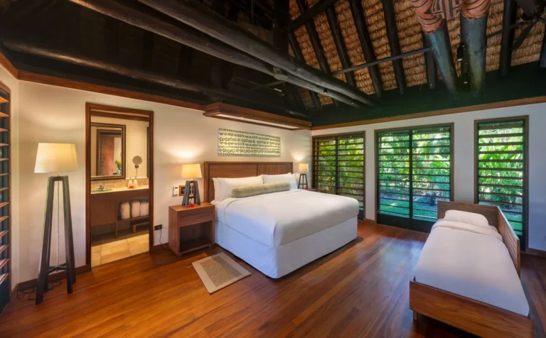 Bedroom of a Gardenview Bure at Jean-Michel Cousteau Resort Fiji, with louvred shutters opening onto tropical gardens