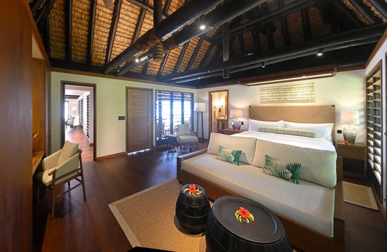 Master bedroom of the Signature Oceanfront Two-Bedroom Bure at Jean-Michel Cousteau Resort Fiji, with dark timber ceiling beams and garden views
