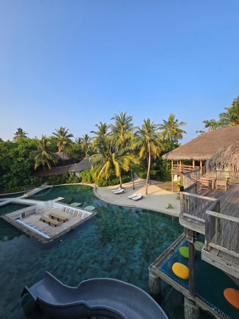 Soneva Fushi beach at golden hour with white sand and calm Indian Ocean lagoon