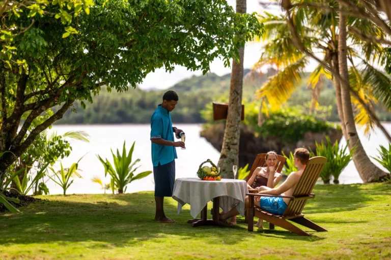 A family enjoys a private picnic lunch on the beach, served by resort staff at Jean-Michel Cousteau Resort Fiji