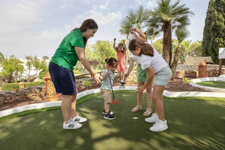 Kinder versuchen sich mit einer Betreuerin am Minigolf-Putt