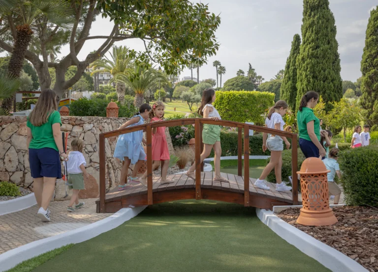 Kindergruppe mit zwei Betreuerinnen auf der Minigolf-Brücke im Resortgarten