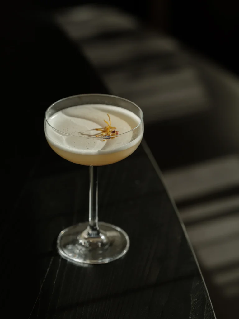 The warm timber-panelled bar at Sonnwies in the early evening, a bartender preparing Aperol spritzes for guests seated on padded stools before floor-to-ceiling shelves of Alpine spirits.
