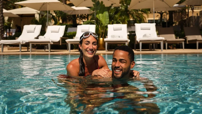 A couple wearing swim goggles laughing together in the pool at Four Seasons Resort Orlando