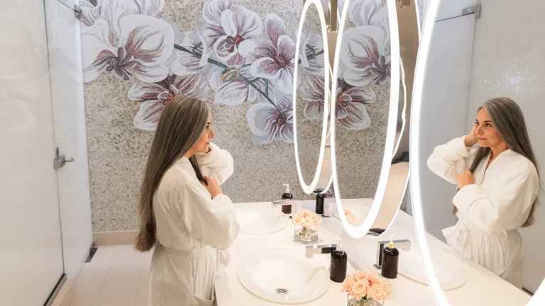 Two women in spa robes at a lit vanity mirror before a treatment at Four Seasons Resort Orlando