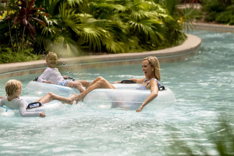 A mother and two children floating together on inner tubes in the lazy river at Four Seasons Resort Orlando