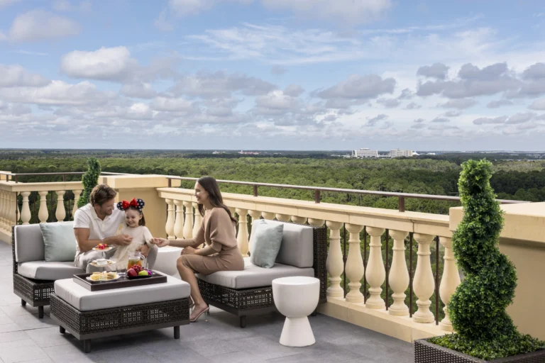 A family of three relaxing on a private balcony terrace with resort and woodland views at Four Seasons Resort Orlando