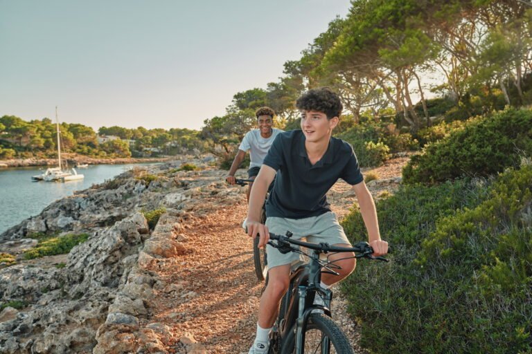 Children cycling along a resort path on family bikes, Ikos Resorts