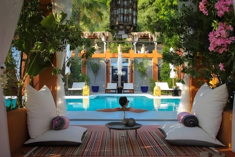 Private terrace lounge cabana with cushioned daybeds beside a deluxe suite plunge pool framed by oleander and palms