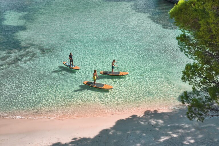 Aerial of paddleboarders in clear water at an Ikos resort beach