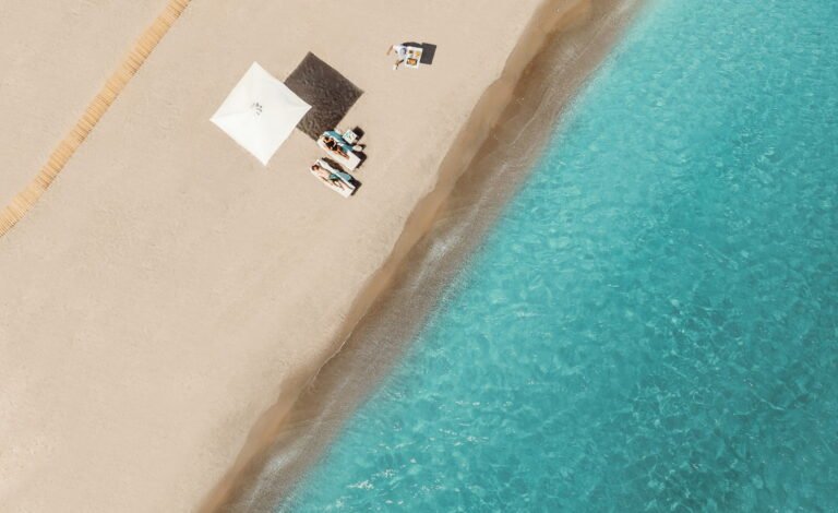 Couple relaxing on the beach with butler service at Ikos Dassia