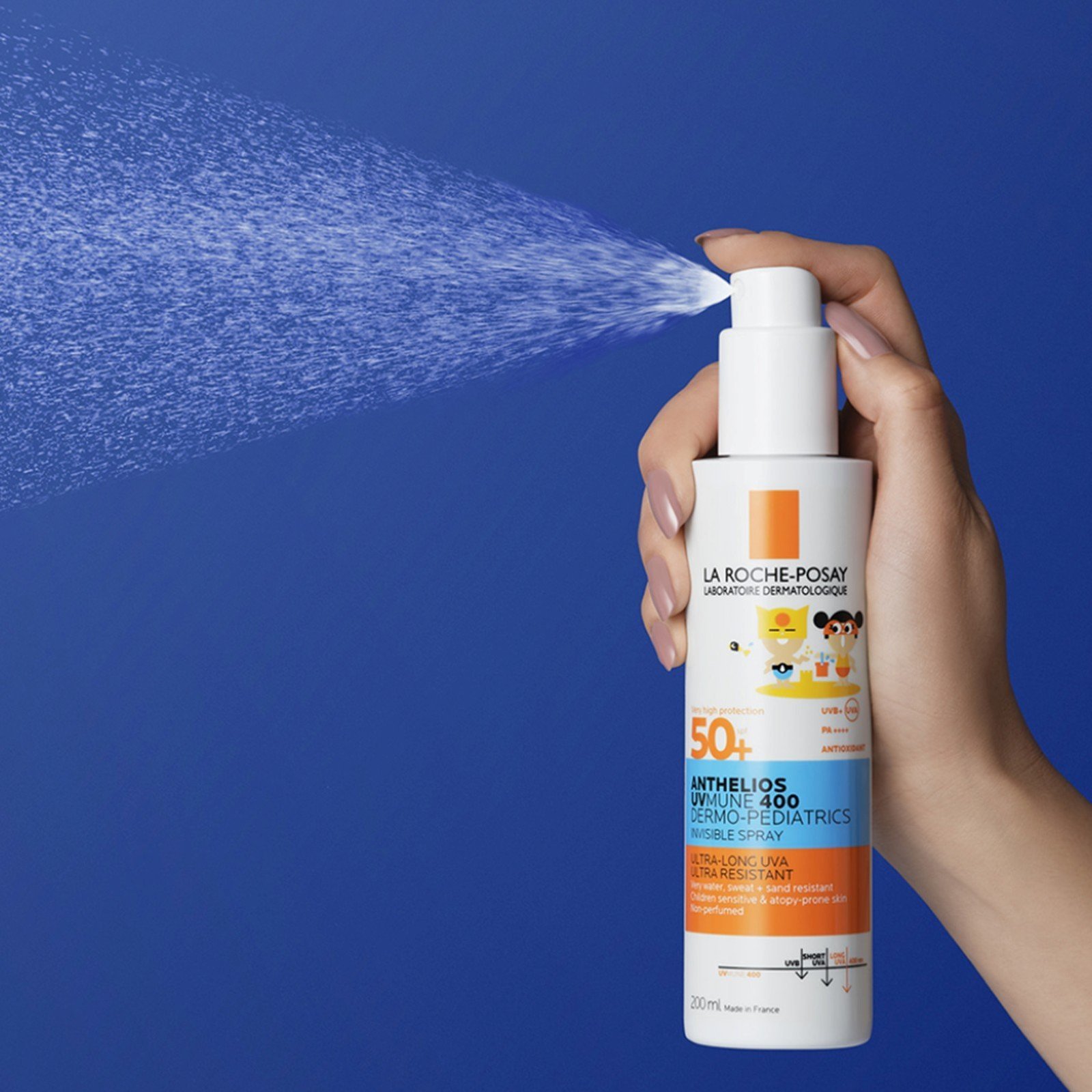 Hand holding the La Roche-Posay Anthelios Dermo-Pediatrics SPF 50+ spray and releasing a fine invisible mist