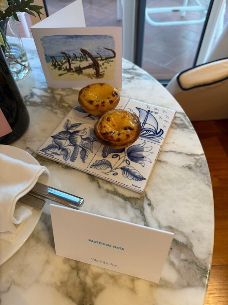 Pasteis de nata served on azulejo tiles with a Vila Vita Parc card