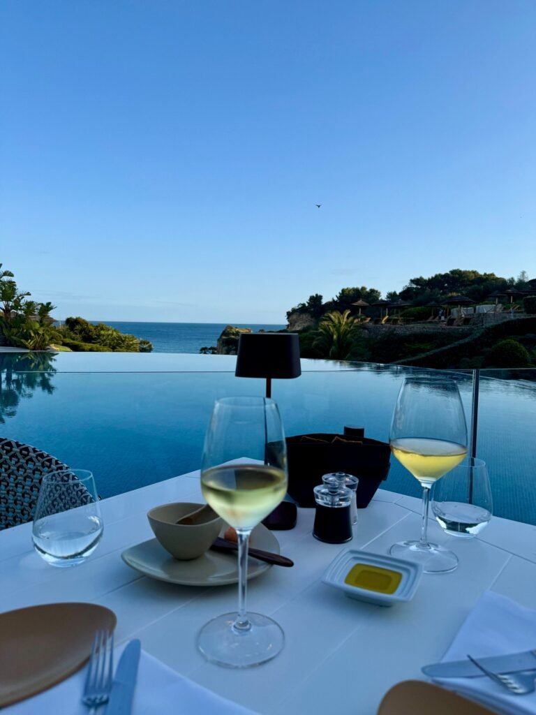 Dinner table set with white wine and a sea view at dusk, Vila Vita Parc