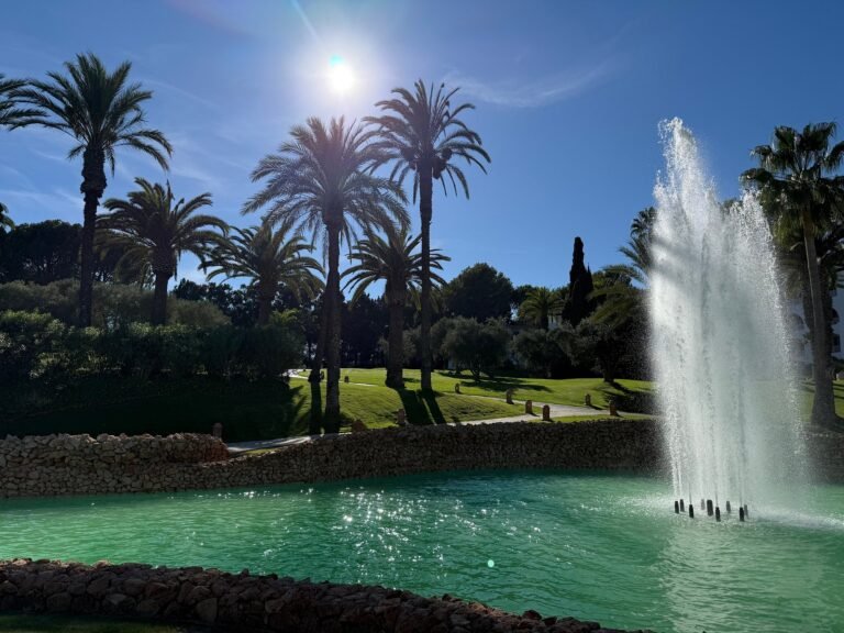 Garden fountain lake fringed by palms in sunlight at Vila Vita Parc