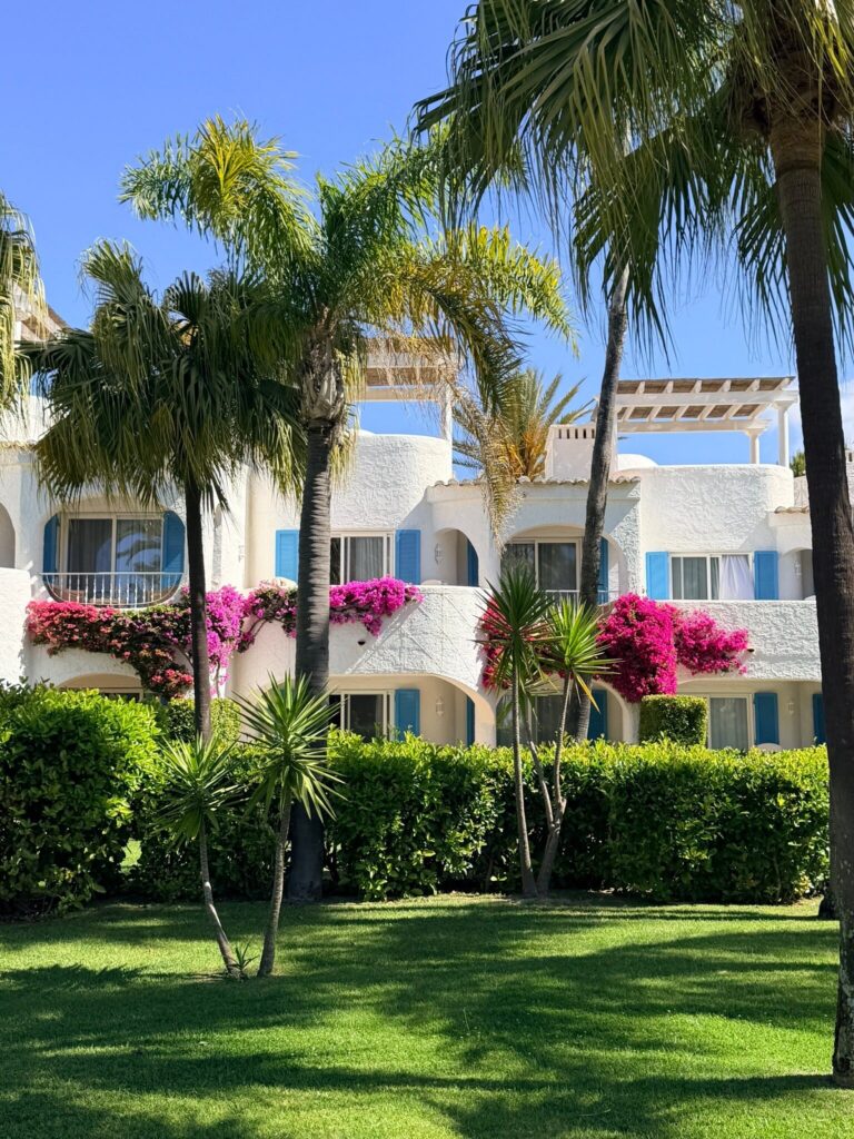 Whitewashed garden-facing apartments with palms and flowers at Vila Vita Parc