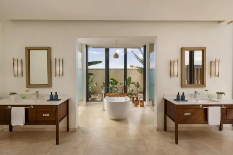 Villa bathroom with twin vanities and a freestanding tub framed by a tropical garden view at Six Senses La Sagesse