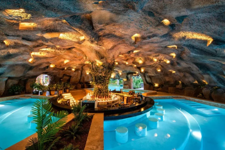Cave-themed swim-up bar in an illuminated grotto pool at Regnum The Crown