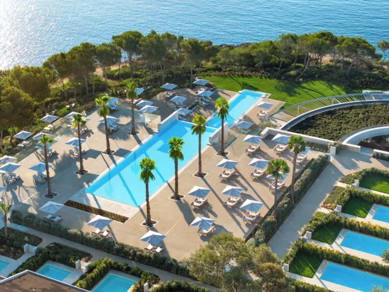 Large resort swimming pool with loungers and landscaped surroundings
