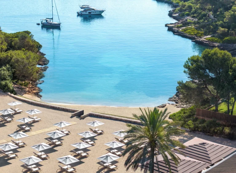 Outdoor swimming pool surrounded by Mediterranean landscaping at Ikos Porto Petro