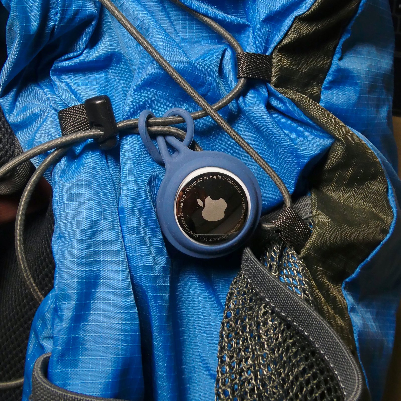 Apple AirTag attached to a backpack strap via keychain loop