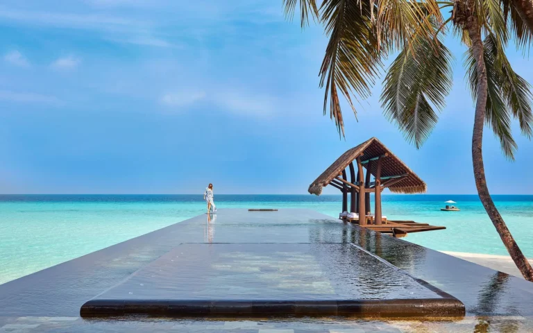 Resort swimming pool at One&Only Reethi Rah with tropical garden and lagoon beyond
