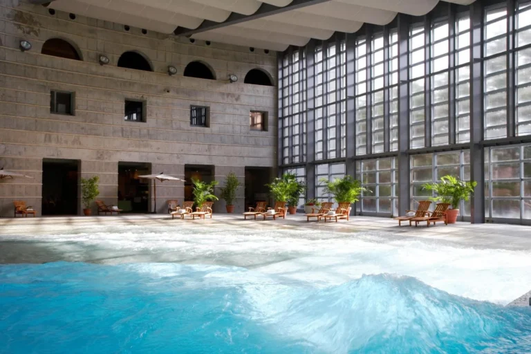 Indoor wave pool and lounge terrace beneath floor-to-ceiling windows at RISONARE Yatsugatake