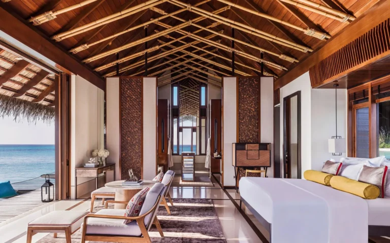 Water villa bedroom interior at One&Only Reethi Rah with ocean views through floor-to-ceiling windows