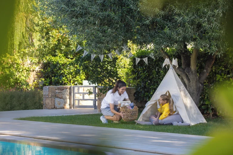 A Sani Explorers team member and a young guest playing at a garden teepee tent