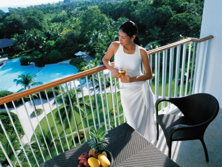 A guest enjoying the room balcony overlooking the pool at Shangri-La Mactan, Cebu