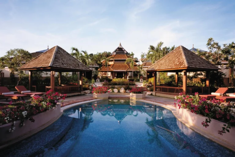 A resort pool flanked by two traditional thatched-roof pavilions at Shangri-La Mactan, Cebu