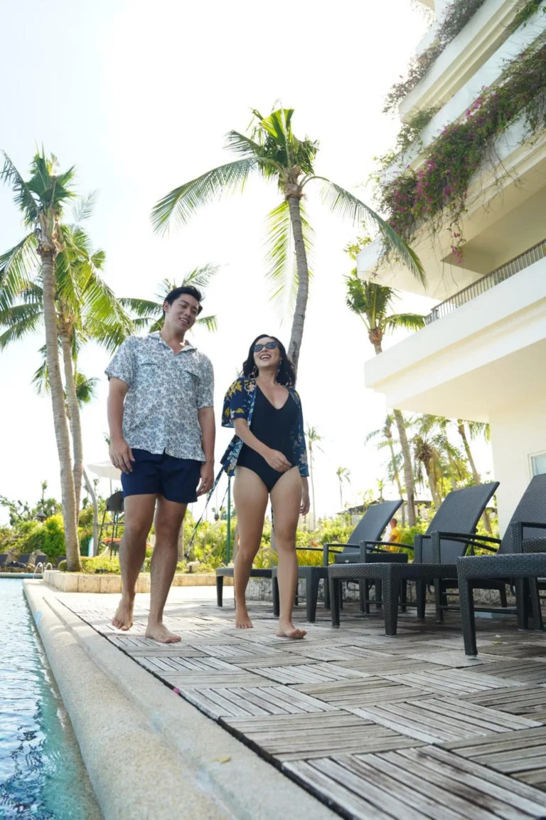 Guests walking poolside beneath palm trees at Shangri-La Mactan, Cebu