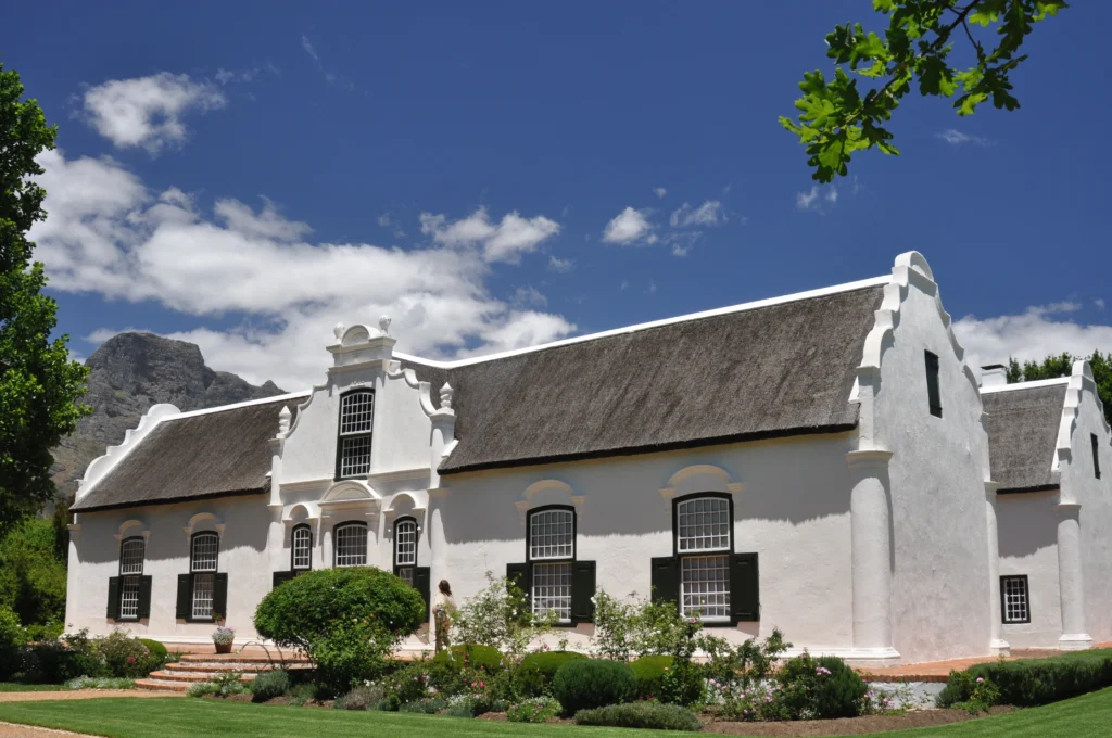 The historic white-gabled Cape Dutch manor house at Boschendal wine estate with mountains behind