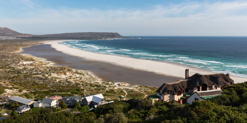 The long white curve of Noordhoek Beach on the Cape Peninsula with turquoise Atlantic surf and Chapman's Peak beyond