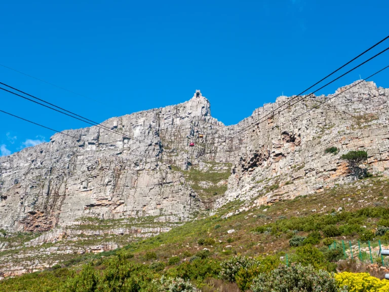 Table Mountain's cliff face with the red and yellow Aerial Cableway cars crossing mid-cable