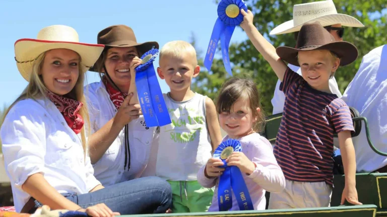 A counselor and children hold up blue ribbons won at the ranch's kids' shodeo event