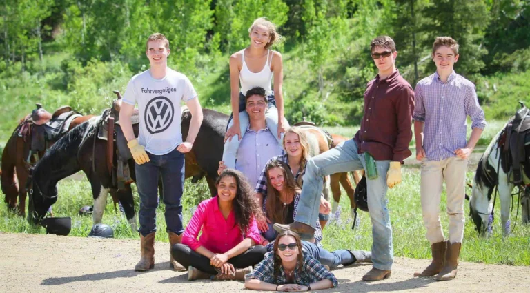 A group of teenagers poses with horses as part of C Lazy U Ranch's teen program