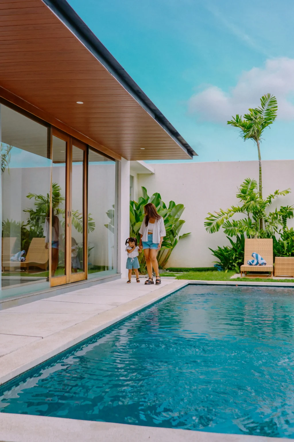 parent and young child walking together along a private pool villa terrace, calm luxury family travel