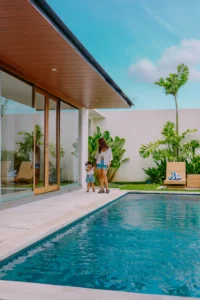 parent and young child walking together along a private pool villa terrace, calm luxury family travel