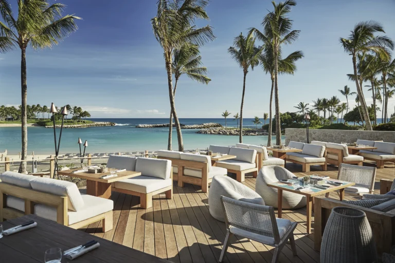 Waterfront outdoor dining terrace at Mina's Fish House overlooking the Ko Olina lagoon, palm trees and ocean