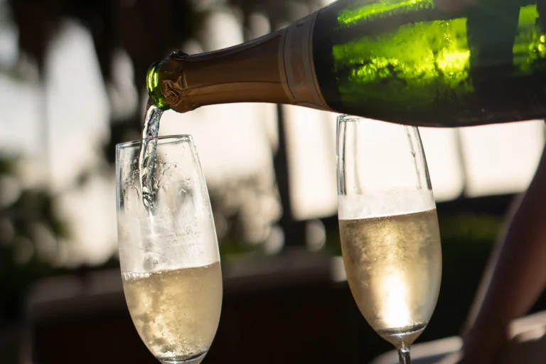Champagne poured into two flutes at golden hour on an outdoor terrace at Four Seasons Resort Oahu at Ko Olina