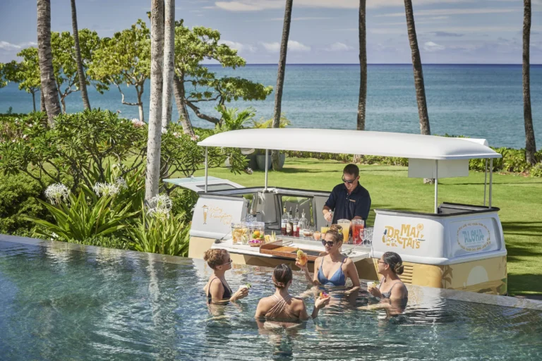 Guests in the infinity pool are served cocktails from the Dr. Mai Tai's vintage mobile bar at Four Seasons Resort Oahu