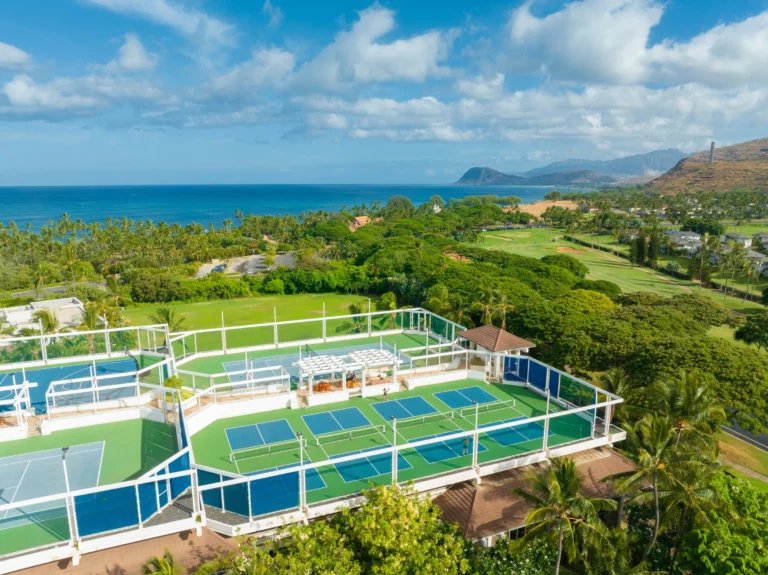 Aerial view of the resort tennis and pickleball court complex with Pacific Ocean and Oahu mountains behind