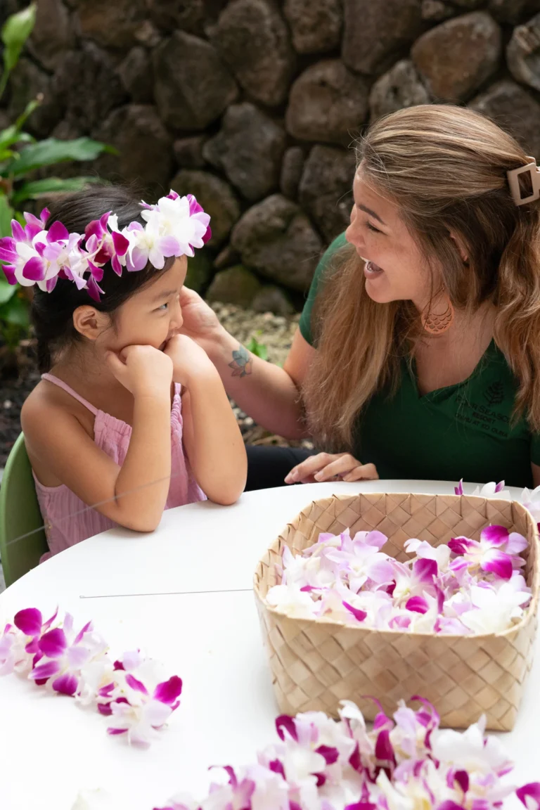 A girl wearing a flower crown with a resort counsellor at Four Seasons Resort Oahu