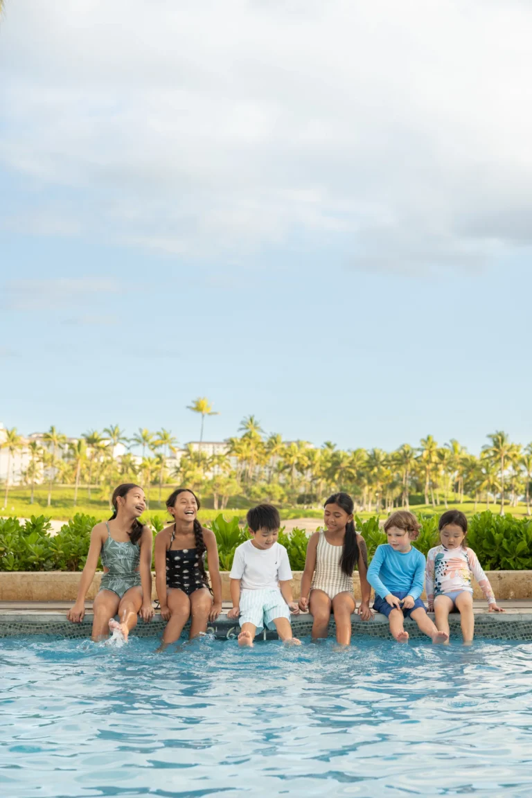A group of children sitting along the edge of the pool at Four Seasons Resort Oahu at Ko Olina