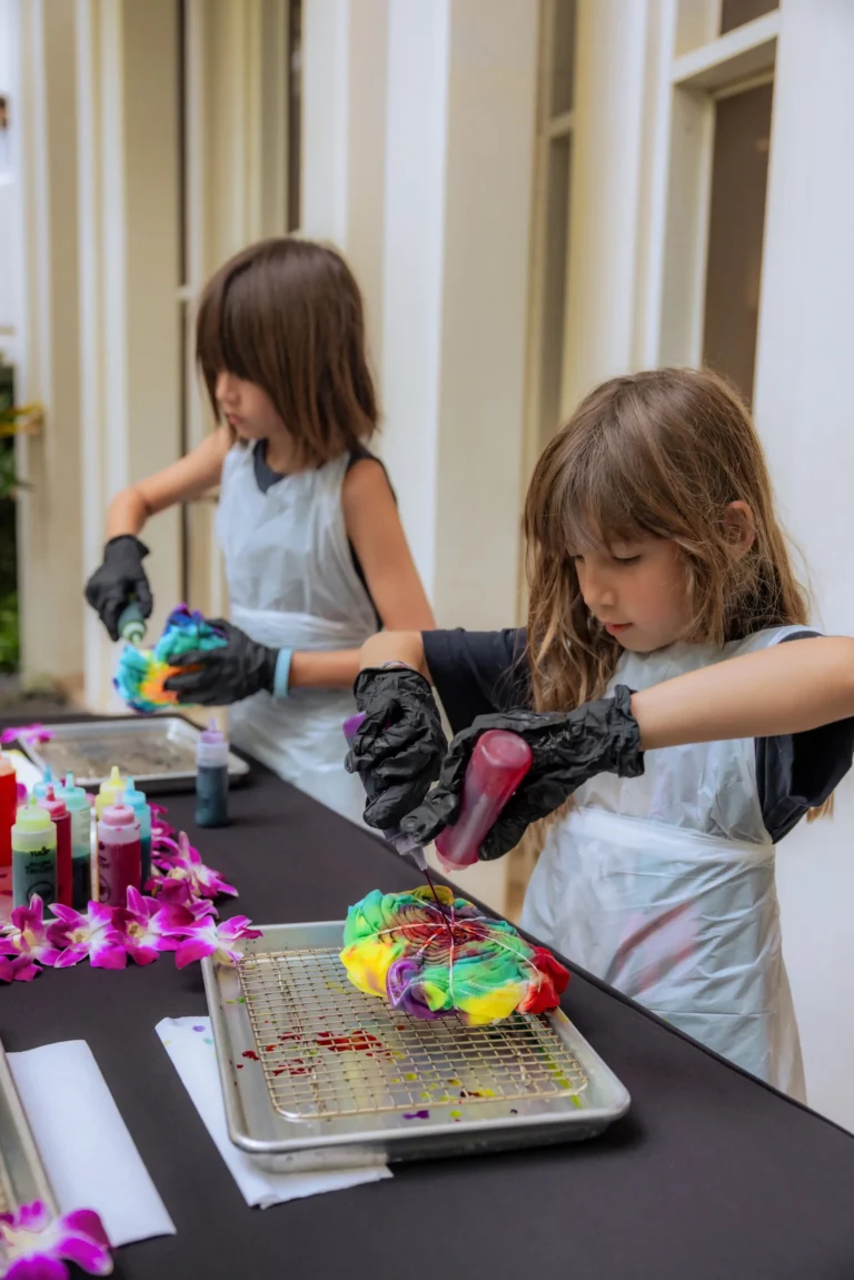 Two children in gloves working on a tie-dye craft session at Camp Kohola, Four Seasons Resort Oahu