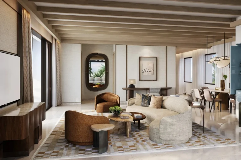 Spacious family suite living room at Jumeirah Al Naseem with curved sofas, a kitchen bar with bar stools, wood beam ceiling, ceiling fan, and dual balcony doors open to a sea-view terrace